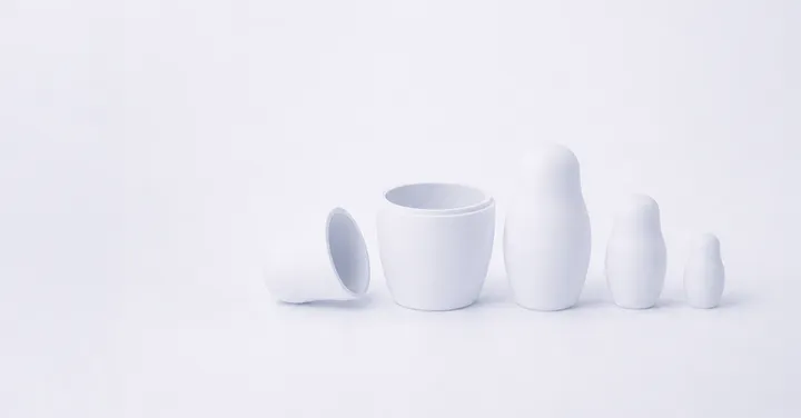 Weiße, ineinandergeschachtelte Matroschka-Puppen auf hellem Grund, die größte geöffnet mit Blick auf die innere Figur – Sinnbild dafür, dass der belegbare Unternehmenswert erst unter der Oberfläche sichtbar wird