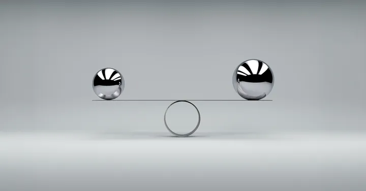 Zwei Metallkugeln im Gleichgewicht auf einer Wippe als Symbol für Stabilisierung, Tragfähigkeit und finanzielle Balance